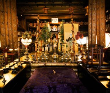 Ornate Buddhist altar with lanterns, gilded statues, wooden pillars and ceremonial offerings in a temple hall