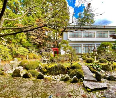 Stone path through moss garden with trees and traditional ryokan building at Koyasan Daienin, Wakayama