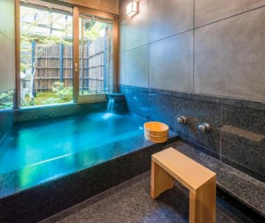 Indoor stone bath with wooden stool, washing faucets and garden view at Ekoin Temple, Koyasan, Wakayama