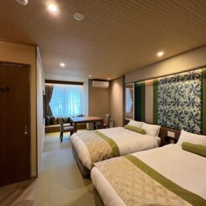 Twin beds on tatami floor with low table and window with curtains at Yurara Marukyō, Kinugawa, Tochigi