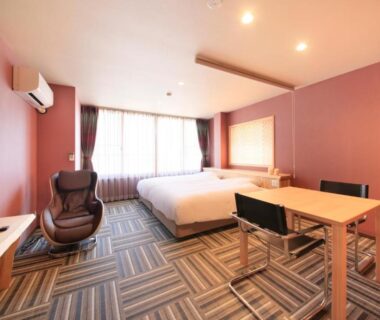 Spacious modern room with bed, lounge chair and desk at Yurara Marukyō Kinugawa Onsen Tochigi