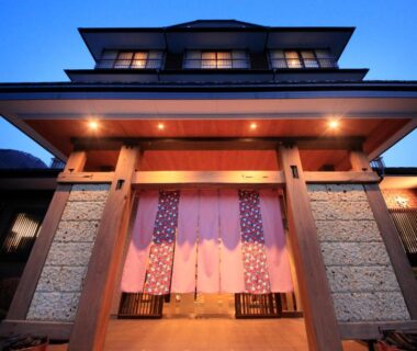 Warmly lit entrance with noren curtains and wooden beams at dusk, Yurara Marukyō, Kinugawa Onsen, Tochigi