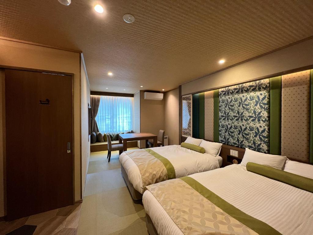 Tatami Twin Room Yurara Marukyō Kinugawa Tochigi Twin beds on tatami floor with low table and window with curtains at Yurara Marukyō, Kinugawa, Tochigi