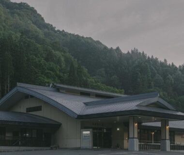 Low-slung ryokan building with covered entrance set against forested mountains in Nagano, Chūbu region