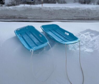 Two blue sleds on fresh snow outside Hôtel et cottages Kinasa no Yu in Nagano