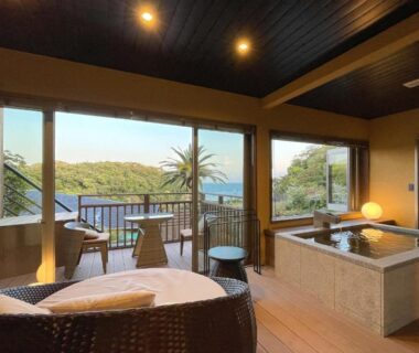 In-room wooden bath and seating with balcony overlooking coastal greenery at 鵜原館 -Ubarakan- in Chiba