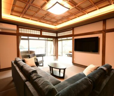 Tatami room with sofa, low table, shoji screens and TV at Ubarakan in Chiba, Kanto