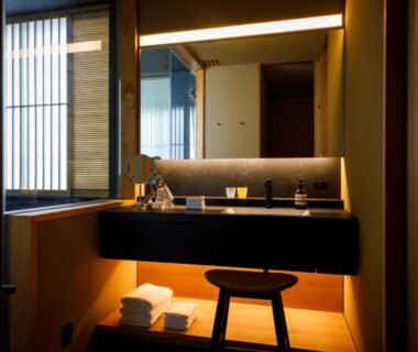 Illuminated sink area with wooden stool and folded towels at 黒梅屋 Kurumiya Ishikawa