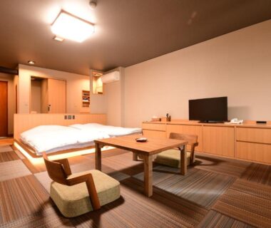 Spacious tatami room with low table, floor chairs, twin low beds and wooden cabinetry at a Chiba ryokan