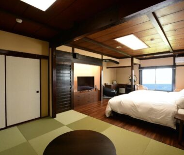 Tatami area with low table and Western bed, shoji doors and TV in ryokan room at Kuroshio no yado Rinkaisou